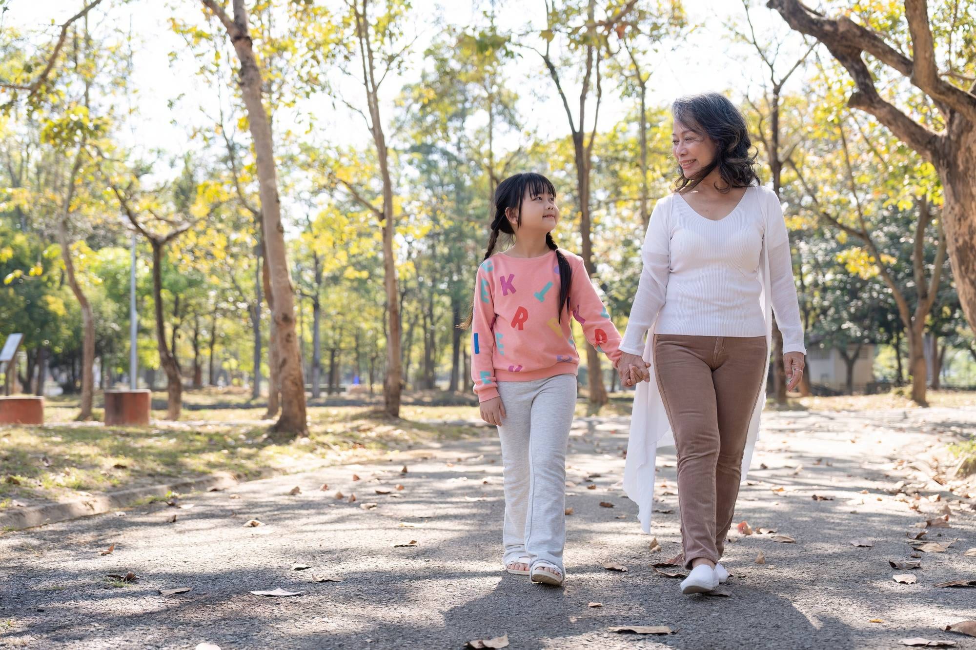 Happy grandmother and grandchild walking in public park