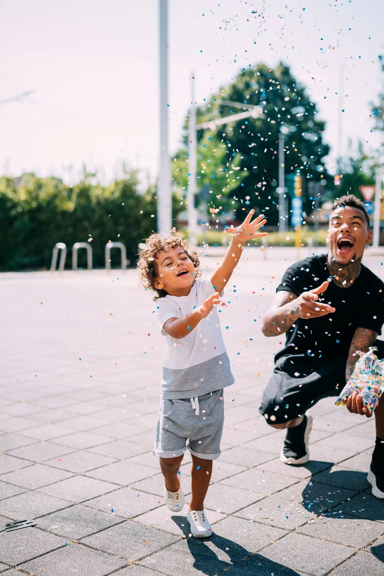 Father and son playing with confetti in park