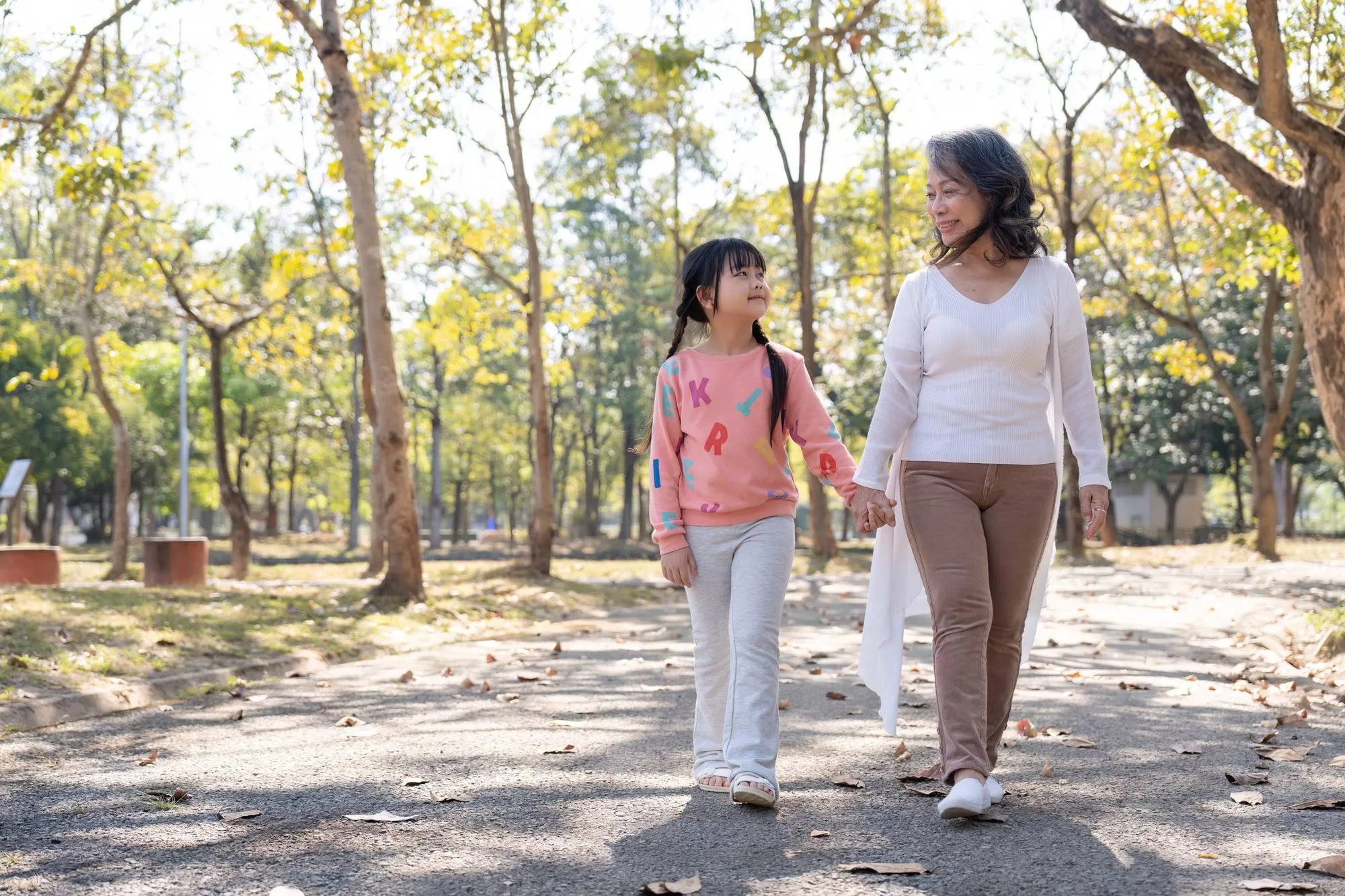 Happy grandmother and grandchild walking in public park