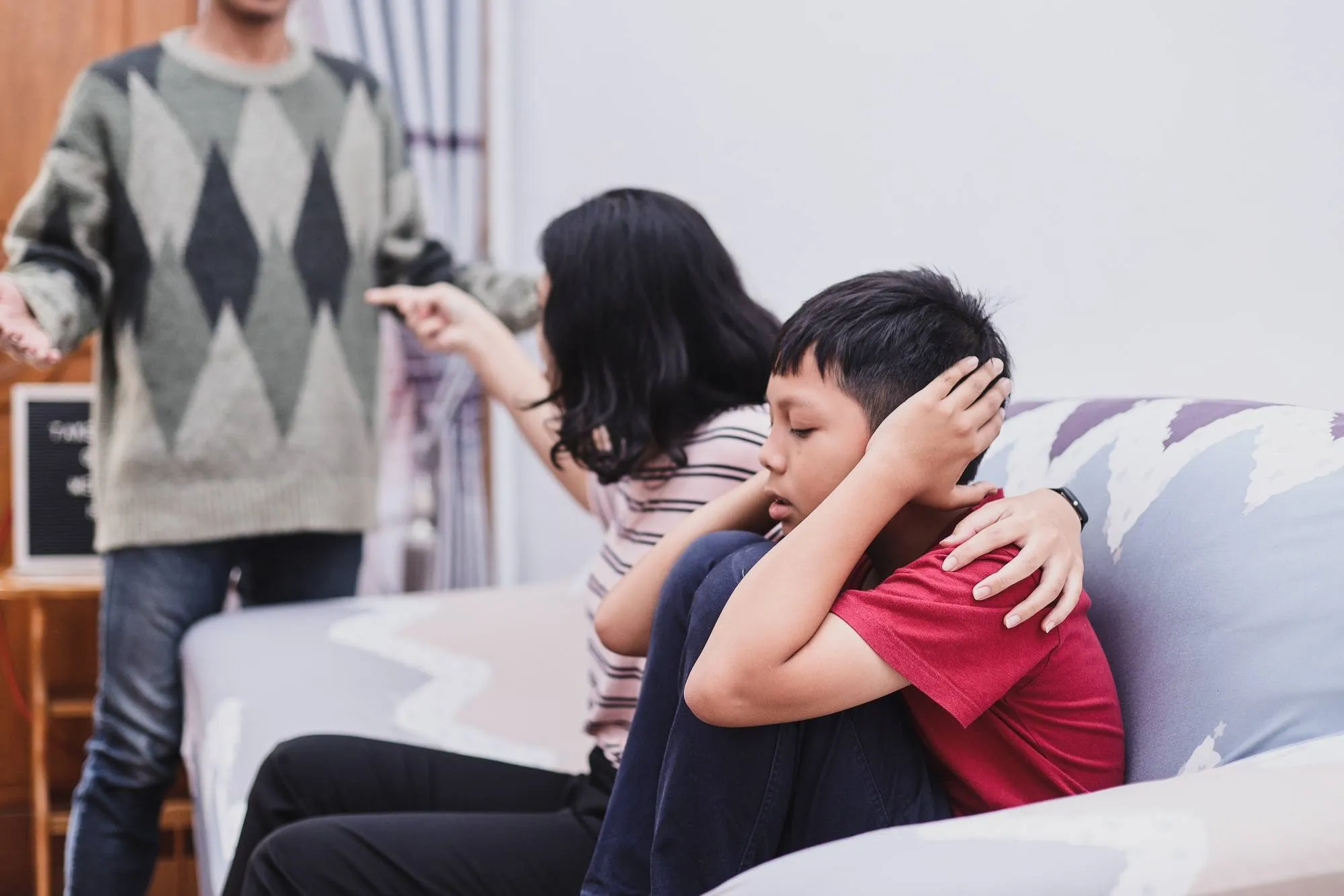 Parents fighting and child crying and closing ears by hands