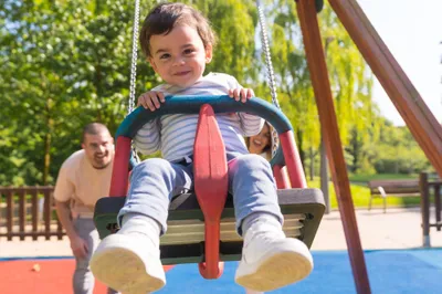 Parents swinging a small child at the playground